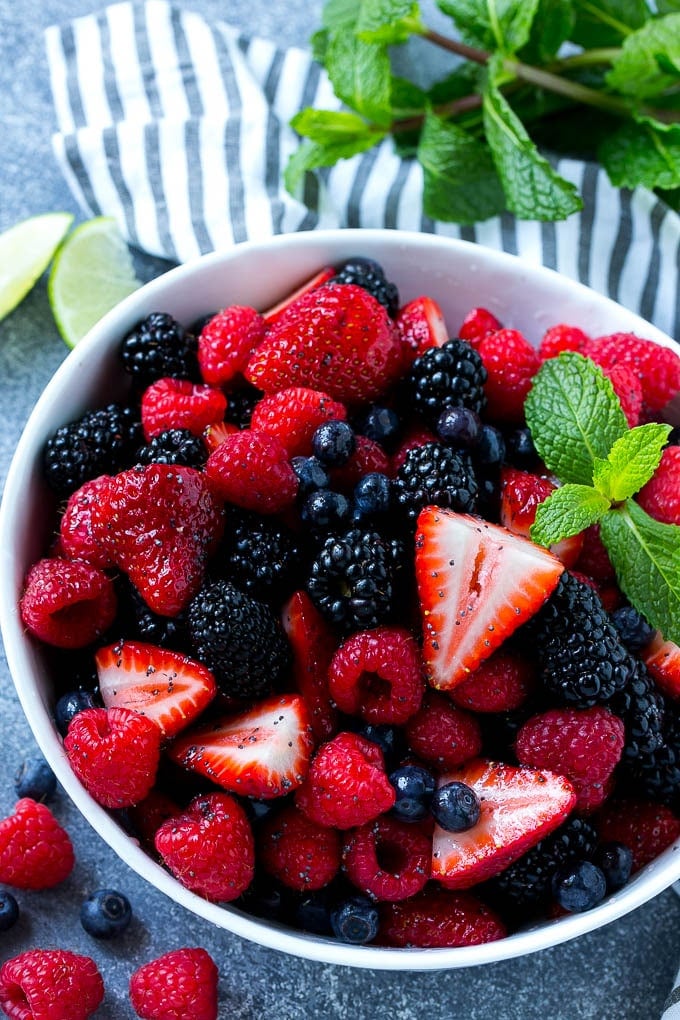 A bowl of berry fruit salad tossed in a honey lime dressing and garnished with fresh mint.