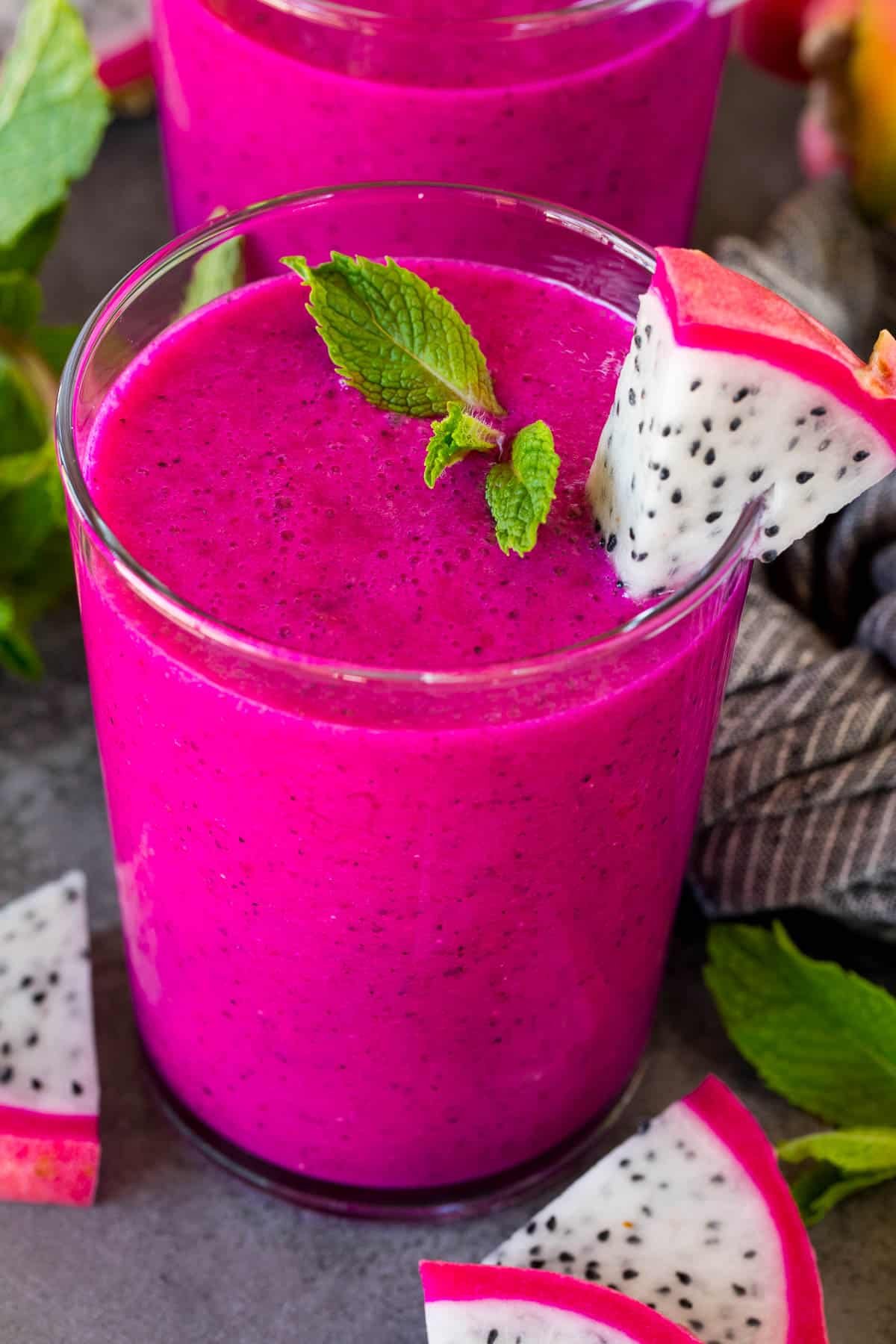 A glass of dragon fruit smoothie garnished with a mint sprig.