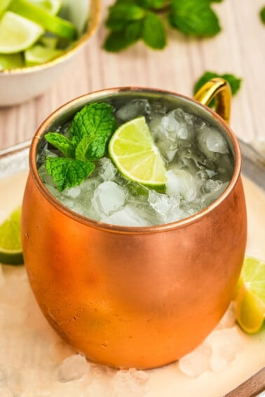 An Irish mule drink in a copper mug topped with a lime and mint sprig.