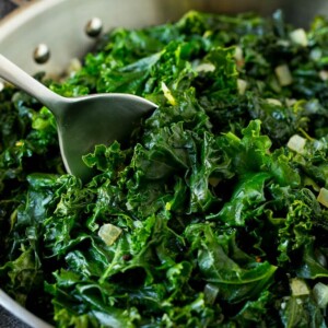 A pan of sauteed kale with a serving spoon in it.