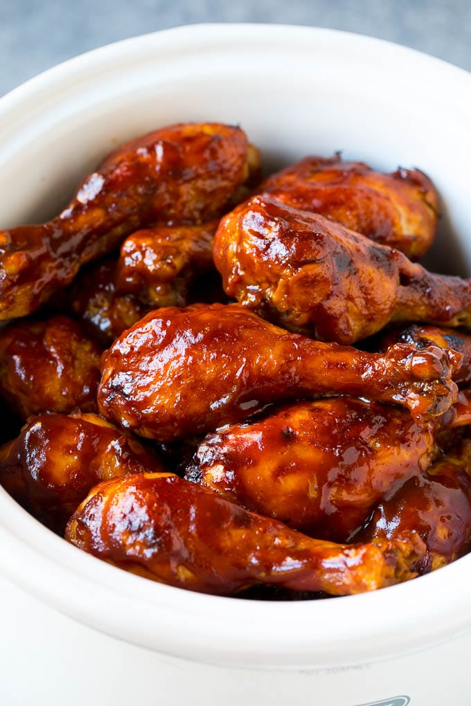 Slow cooker chicken drumsticks coated in BBQ sauce inside a crock pot.